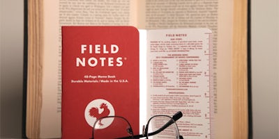 The 12th Edition of the Tournament of Books. A red rooster notebook laying on an open book.